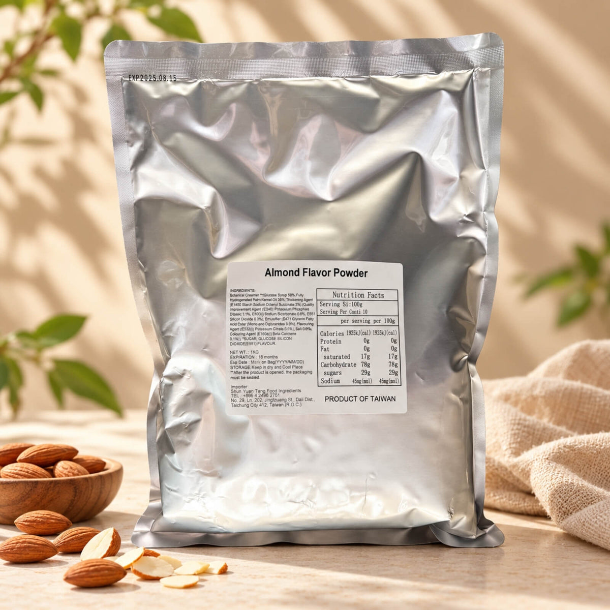 1kg Almond Flavour Powder in a silver foil package, displayed with whole almonds and almond slices on a warm beige background with natural sunlight.