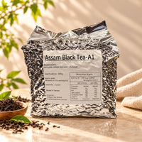 600g package of Assam Black Tea A1 in a silver foil bag with a product label, displayed alongside loose black tea leaves.