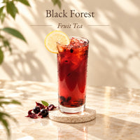 Iced Black Forest Fruit Tea with a deep ruby-red colour, served in a tall glass with ice and a lemon slice garnish.