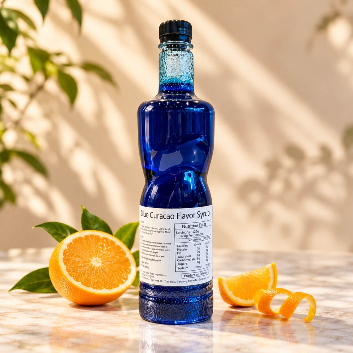 Bottle of Blue Curacao Flavoured Syrup filled with vibrant deep blue syrup and topped with a black screw cap, displayed alongside fresh orange slices.