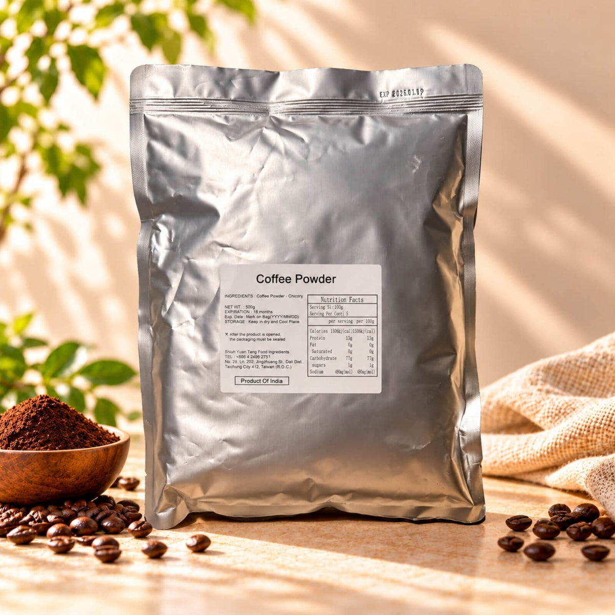 Coffee Powder in a 500g silver foil package with product label, displayed with roasted coffee beans and ground coffee in natural sunlight.