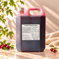 5kg container of Cranberry Flavoured Syrup with dark red syrup, a white screw cap and product label, displayed alongside fresh cranberries.