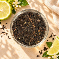 Loose Earl Grey black tea leaves in a clear glass bowl, showing their dark brown colour and dried leaf texture, displayed alongside bergamot citrus slices.