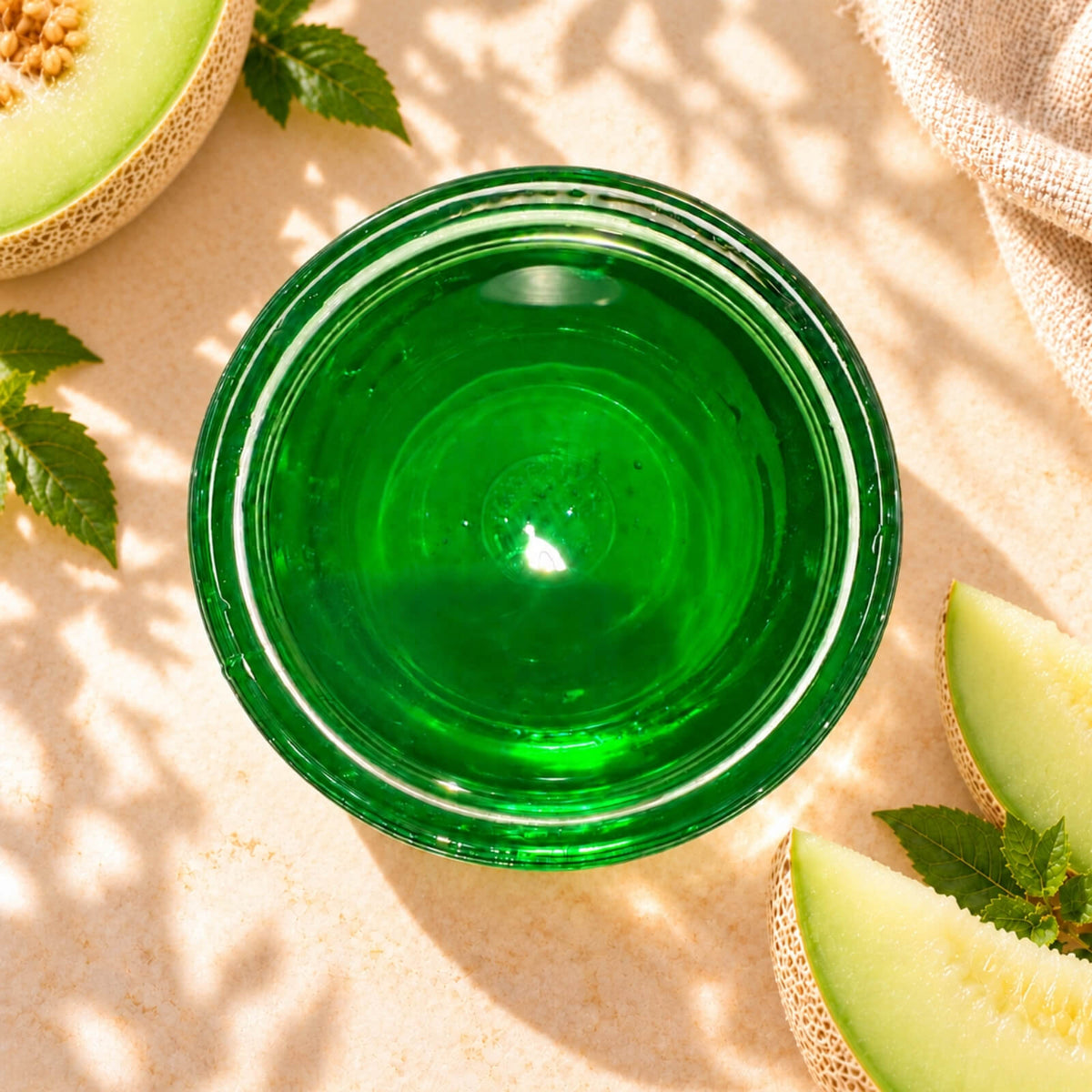 Honeydew flavoured syrup in a glass bowl, showing its vibrant green colour and smooth, glossy texture, displayed alongside fresh honeydew melon slices.