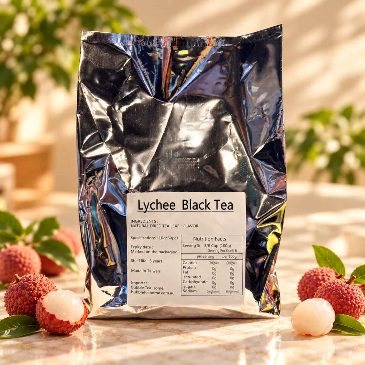 Lychee Black Tea in a silver foil package containing 60 tea bags of 10g each, displayed alongside whole and peeled lychees on a warm neutral background.