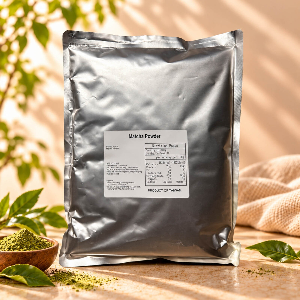 Matcha Powder in a 1kg silver foil package with a product label, displayed alongside a small wooden bowl of green matcha powder under warm natural sunlight.