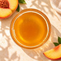 Peach flavoured syrup in a glass bowl, showing its golden-orange colour and smooth texture.