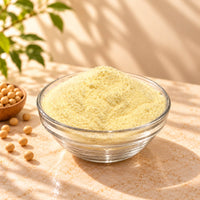 Soy Milk Powder in a clear glass bowl, showing its pale yellow colour and fine texture, with soybeans on a warm beige background.