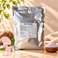 Taro Powder 1kg in a silver foil package, displayed with fresh taro roots, sliced taro and a wooden bowl of purple taro powder on a warm beige background.